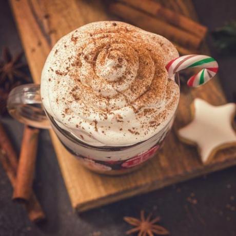 skodelica vroče čokolade s stepeno smetano in sladkarijami v prijetnem božičnem vzdušju