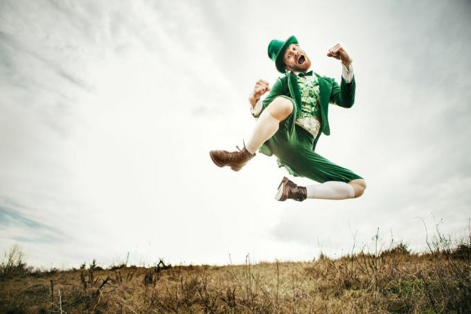 stereotipni irski lik, pripravljen na dan svetega Patrika, skače in pleše na odprtem polju irskega podeželja kopija prostora na nebu in travi