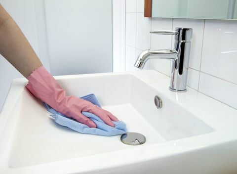 Čiščenje umivalnika: Ženska, ki umivalnik čisti s krpo in rokavicami iz mikrovlaken