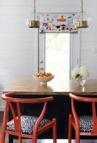 rdeči stoli v beli kuhinji z obloženimi stenami 