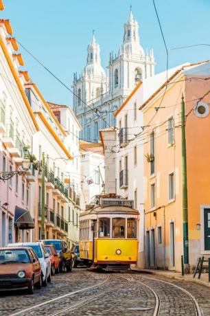 rumeni tramvaj na ozki ulici okrožja alfama v lizboni, portugalska